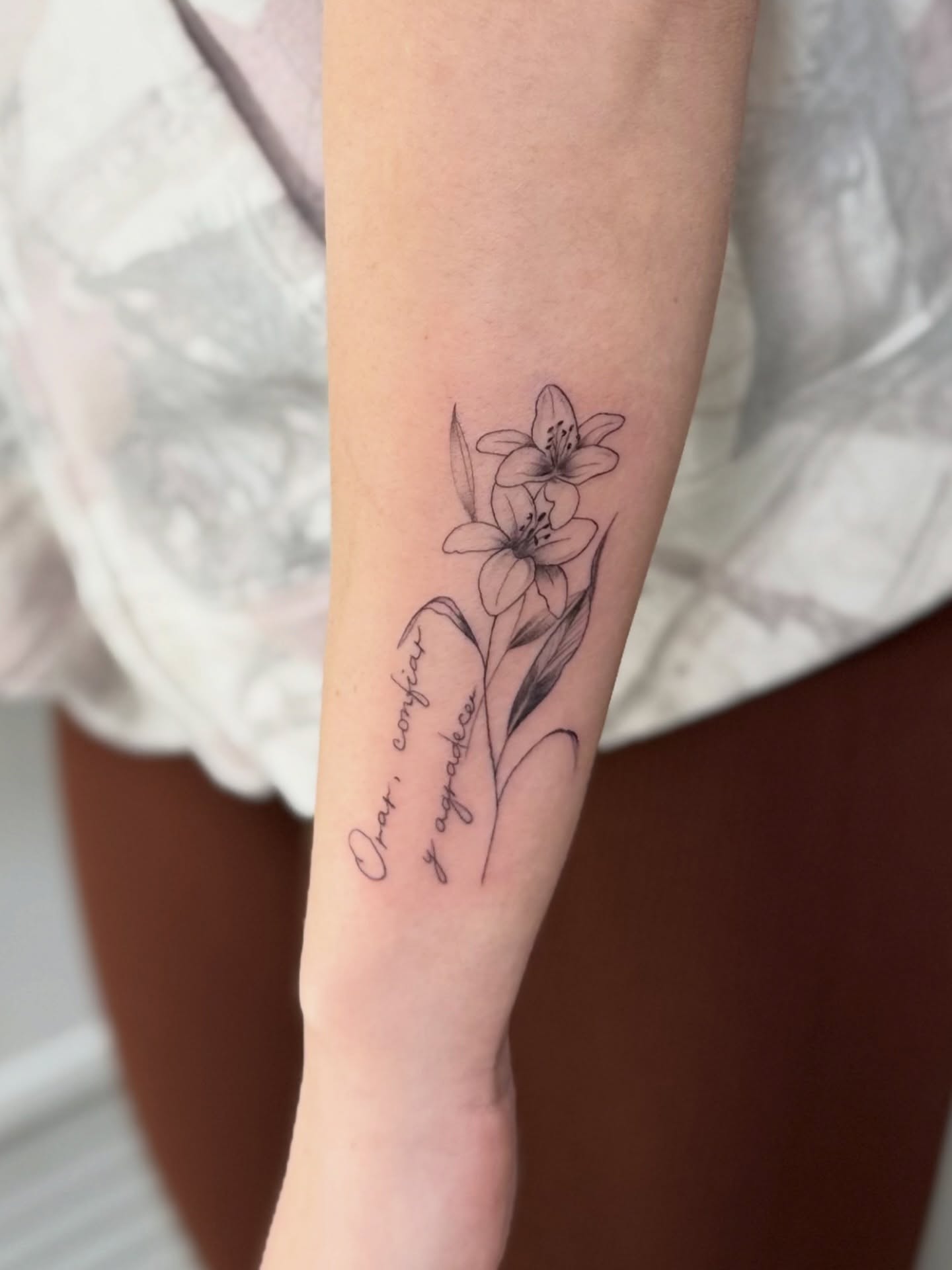 Lily and script tattoo on forearm